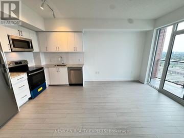Toronto (Humber Heights) condo for rent - A kitchen with white cabinets and a microwave above the stove.
