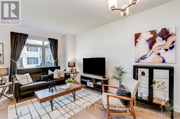Ottawa townhouse for rent - A living room with a black couch, a wooden coffee table, a flat screen TV, and a large painting on the wall.