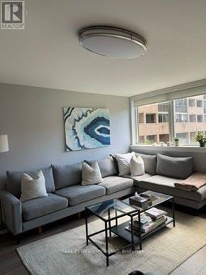 Toronto (Cabbagetown-South St. James Town) condo for rent - A living room with a grey couch, a glass coffee table, and a large abstract painting on the wall.
