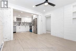Toronto (The Beaches) multi-family for rent - A spacious kitchen and living room with white walls and wooden floors.