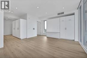 Kitchener condo for rent - A spacious room with wooden flooring and white cabinetry.