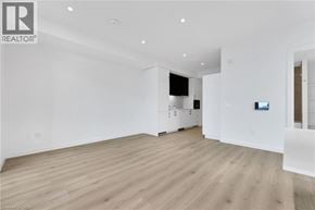 Kitchener condo for rent - A spacious room with wooden flooring and white walls.