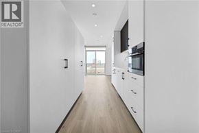 Kitchener condo for rent - A long, narrow, white hallway with a kitchen area at the end.