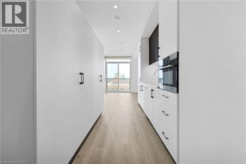 Kitchener condo for rent - A long, narrow, white hallway with a kitchen area at the end.