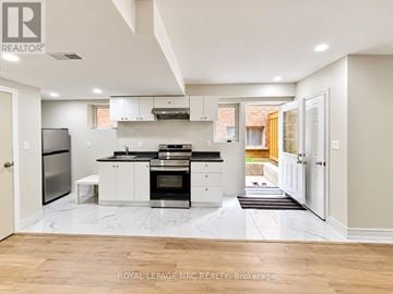 Orillia apartment for rent - A modern kitchen with white cabinets and a black stove top oven.