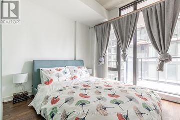 Toronto (Waterfront Communities) condo for rent - A bedroom with a large bed and a window with curtains.