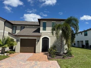Port St Lucie apartment for rent - A house with a brown garage door and a palm tree in front.