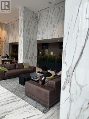 Mississauga (City Centre) condo for rent - A man is sitting on a couch using a laptop in a room with marble walls.