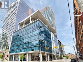 Toronto (Moss Park) condo for rent - A modern glass building with a white overhang is in the foreground.