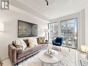 Toronto (Moss Park) condo for rent - A living room with a grey couch, a coffee table, and a large window.
