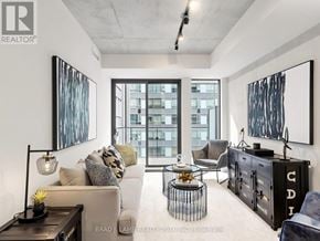 Toronto (Moss Park) condo for rent - A modern living room with a large window and a view of a building outside.