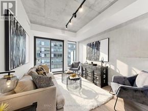 Toronto (Moss Park) condo for rent - A modern living room with a large window and a view of a building outside.