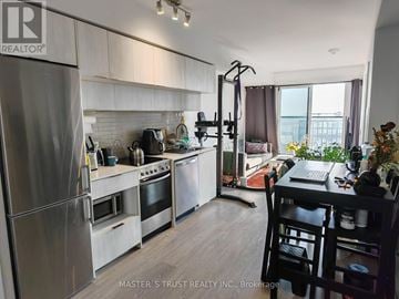 Toronto (Moss Park) condo for rent - A kitchen with stainless steel appliances and a dining table with chairs.