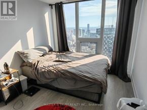 Toronto (Moss Park) condo for rent - A bedroom with a large bed and a city view through the window.