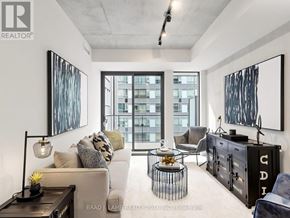 Toronto (Moss Park) condo for rent - A modern living room with a large window and a view of a building outside.