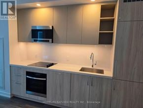 Vaughan (Vaughan Corporate Centre) condo for rent - A modern kitchen with wooden cabinets and a stainless steel oven.