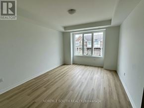 Barrie townhouse for rent - A room with wooden flooring and a large window overlooking a street.