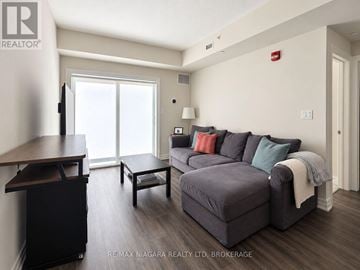 St. Catharines (Lakeport) condo for rent - A living room with a grey couch and a wooden table.