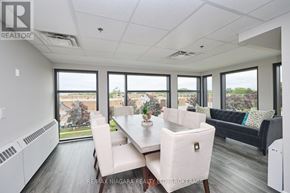 St. Catharines (Lakeport) condo for rent - A dining room with a table set for four and a couch in the background.