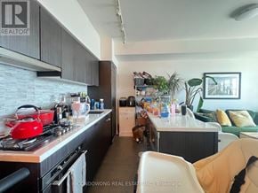 Toronto (Casa Loma) condo for rent - A kitchen with a red kettle on the stove and a white chair in the foreground.