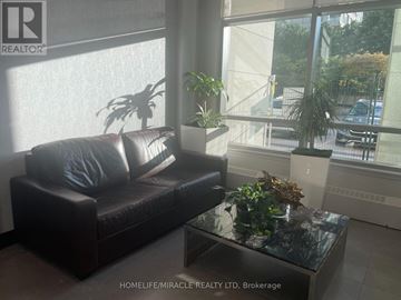 Mississauga (City Centre) condo for rent - A living room with a black couch and a glass table.