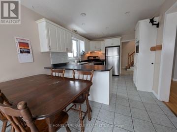 Kitchener apartment for rent - A kitchen with a table and chairs in the foreground and a refrigerator in the background.