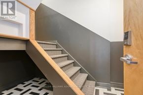 Toronto (Palmerston-Little Italy) condo for rent - A staircase with a wooden handrail and a grey carpeted runner.