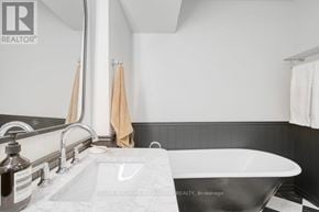 Toronto (Palmerston-Little Italy) condo for rent - A bathroom with a white tub and a sink with a mirror above it.