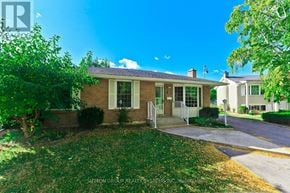 St. Catharines (Lakeport) apartment for rent - A house with a white door and windows is surrounded by greenery.