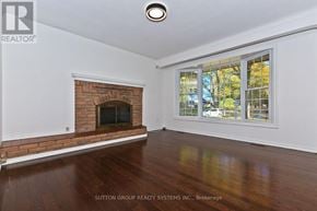St. Catharines (Lakeport) apartment for rent - A room with a fireplace and a window showing trees outside.