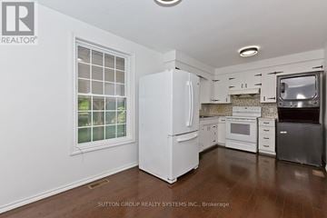 St. Catharines (Lakeport) apartment for rent - A white refrigerator stands in a kitchen with wooden floors and white walls.