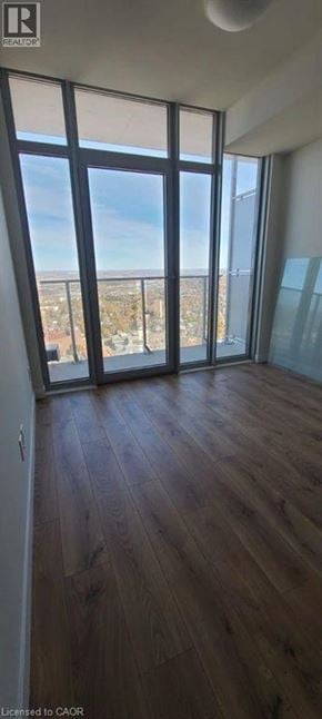 Kitchener condo for rent - A room with wooden floors and large windows overlooking a cityscape.