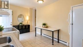 Toronto (Woodbine-Lumsden) duplex for rent - A well-lit kitchen with a sink, a fridge, and a dining table with chairs.
