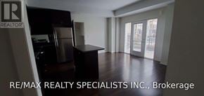 Mississauga (Churchill Meadows) townhouse for rent - A large, empty room with a kitchenette and a view of the city through the windows.