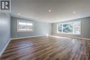 Kitchener apartment for rent - A spacious room with wooden flooring and two windows.