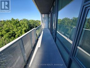 Toronto (Bayview Village) condo for rent - A balcony with a metal railing and glass doors overlooking a forest.