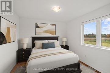 Ottawa apartment for rent - A bedroom with a large bed, two lamps, and a painting on the wall.