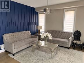 Brampton (Bram West) apartment for rent - A grey sofa and a glass coffee table with a vase of white flowers on it.