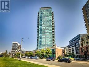 Toronto (Little Portugal) condo for rent - A tall glass building stands in the middle of a city street.