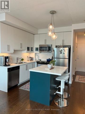 Toronto (Little Portugal) condo for rent - A kitchen with white cabinets and a blue island.
