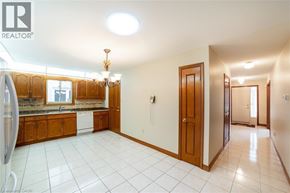 Hamilton apartment for rent - A large, empty kitchen with wooden cabinets and a white tile floor.