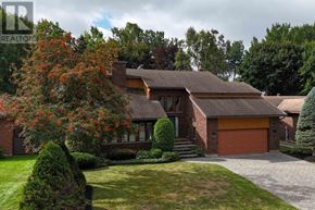 Sault Ste. Marie apartment for rent - A house with a red garage door and a tree with red flowers in front.