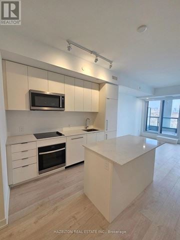 Toronto (Willowdale East) condo for rent - A modern kitchen with white cabinets and a microwave above the stove.