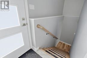 Hawkesbury apartment for rent - A stairway with a wooden handrail and a white door.