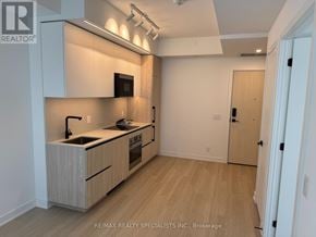 Toronto (Bayview Village) condo for rent - A modern kitchen with wooden cabinets and a white countertop.