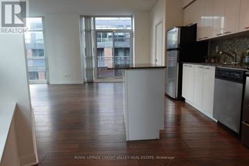 Toronto (Niagara) condo for rent - A kitchen with white cabinets and a black fridge.