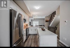Brantford townhouse for rent - A kitchen with a refrigerator, microwave, and oven.