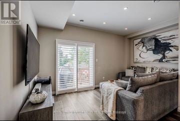Brantford townhouse for rent - A living room with a grey couch, a flat screen TV, and a large painting on the wall.