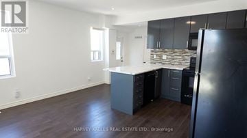 Toronto (Humewood-Cedarvale) multi-family for rent - A kitchen with a black refrigerator and wooden floors.