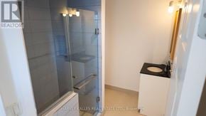 Toronto (Humewood-Cedarvale) multi-family for rent - A bathroom with a glass shower stall and a toilet with a black seat cover.